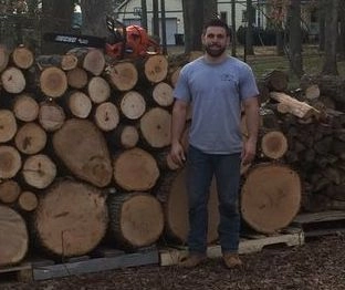 Cody Clauss in front of wood pile